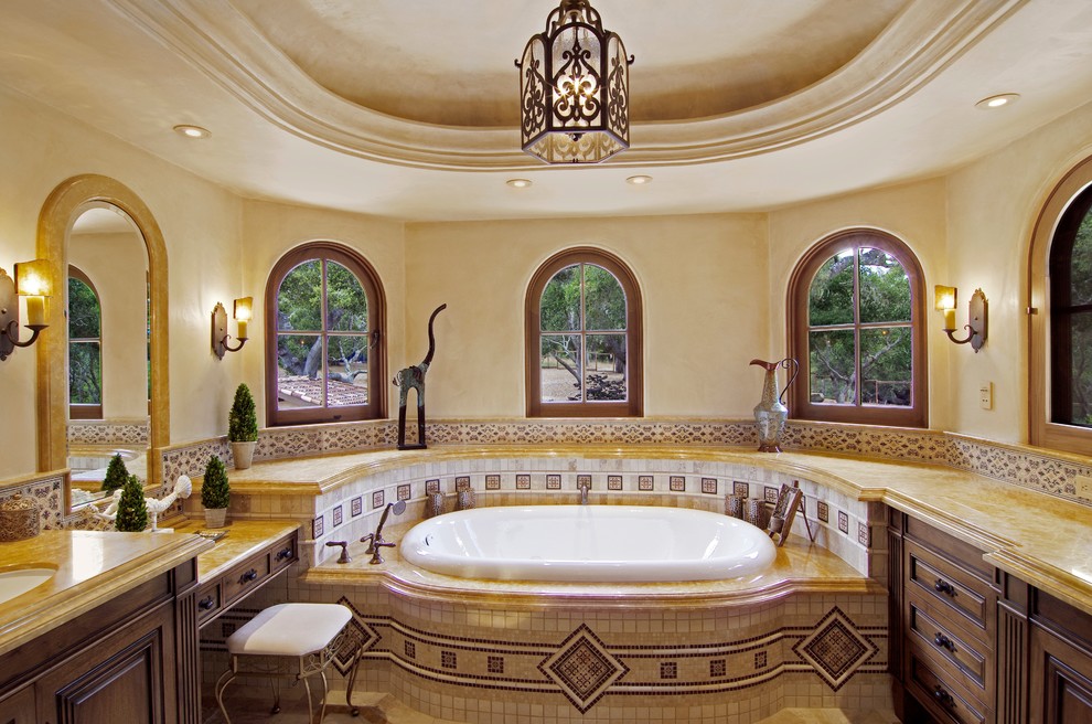 Design ideas for a large mediterranean master bathroom in San Francisco with beaded inset cabinets, medium wood cabinets, a freestanding tub, an alcove shower, a one-piece toilet, beige tile, stone tile, beige walls, porcelain floors, an undermount sink and limestone benchtops.