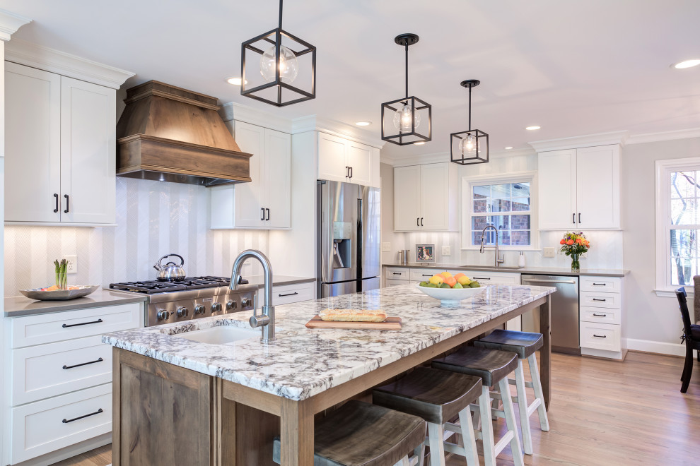 Inspiration for a mid-sized country l-shaped eat-in kitchen in Raleigh with an undermount sink, shaker cabinets, white cabinets, quartz benchtops, white splashback, glass tile splashback, stainless steel appliances, medium hardwood floors, with island, brown floor and grey benchtop.