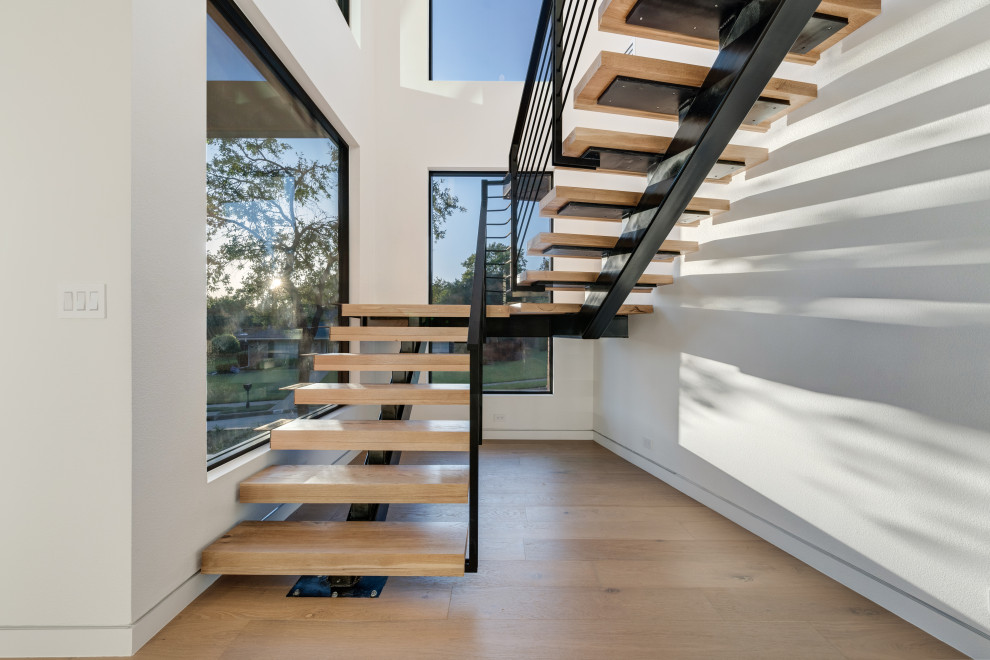 Photo of a midcentury wood floating staircase in Dallas with open risers and metal railing.