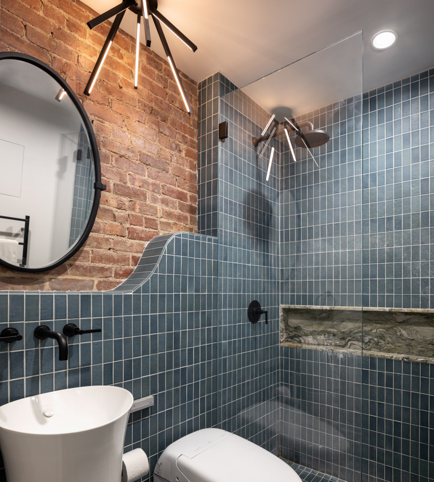 Photo of a small classic ensuite bathroom in New York with a built-in shower, a bidet, blue tiles, ceramic tiles, ceramic flooring, a pedestal sink, tiled worktops, blue floors, a hinged door, a wall niche, a single sink and brick walls.