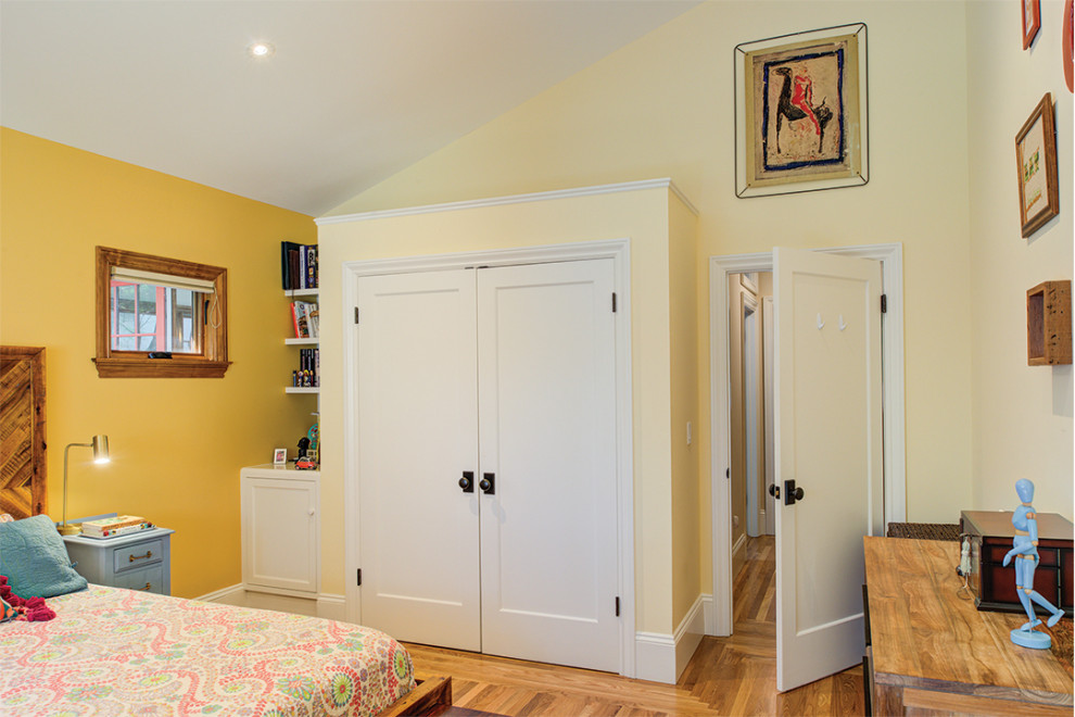 Réalisation d'une armoire encastrée design de taille moyenne et neutre avec un sol en bois brun et un plafond voûté.