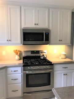Example of a large transitional u-shaped kitchen design with an undermount sink, flat-panel cabinets, white cabinets, solid surface countertops, subway tile backsplash, stainless steel appliances, an island and multicolored countertops