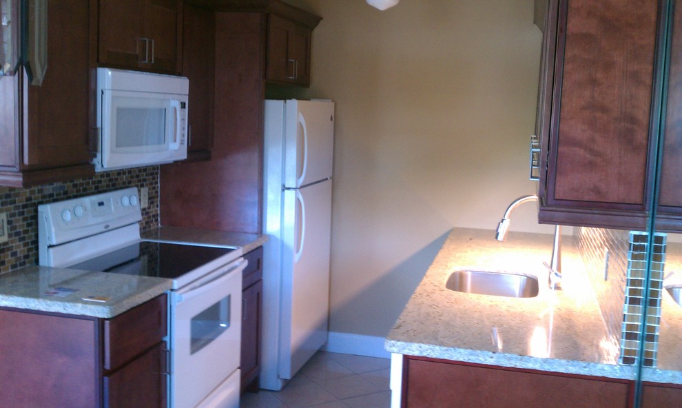 Eat-in kitchen - small transitional galley ceramic tile eat-in kitchen idea in Miami with a single-bowl sink, recessed-panel cabinets, dark wood cabinets, multicolored backsplash, mosaic tile backsplash, white appliances and no island