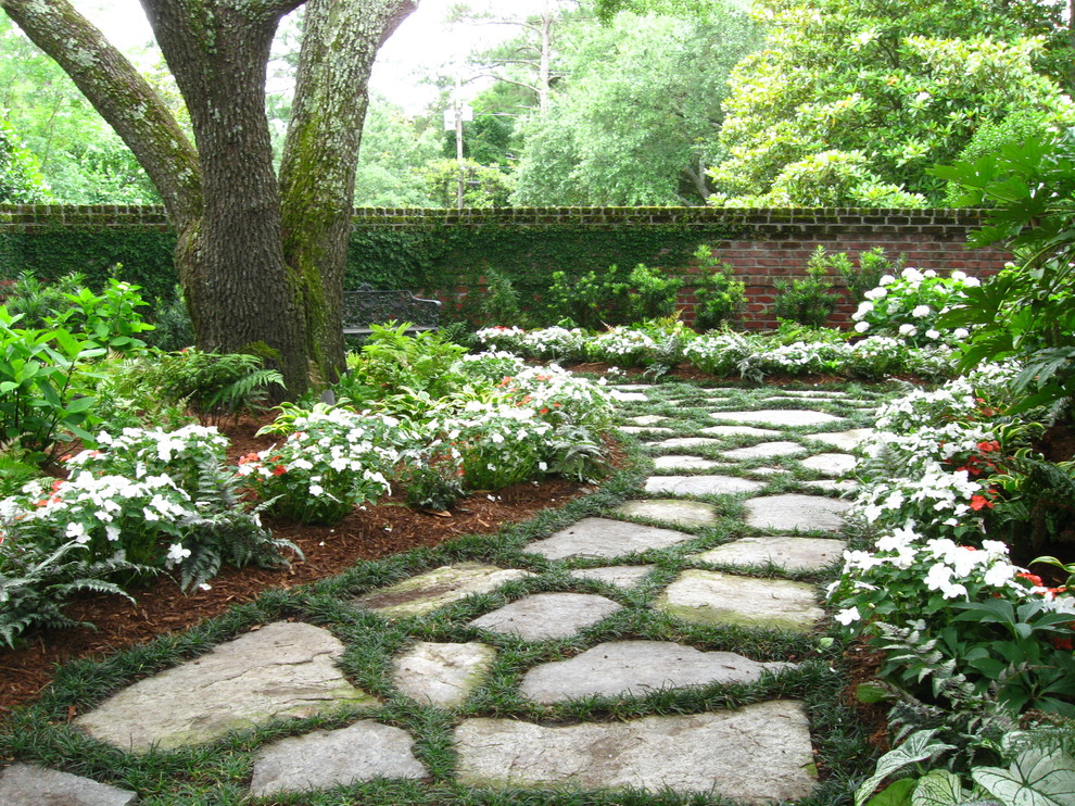 This is an example of a traditional courtyard partial sun garden for summer in Other with a garden path and natural stone pavers.