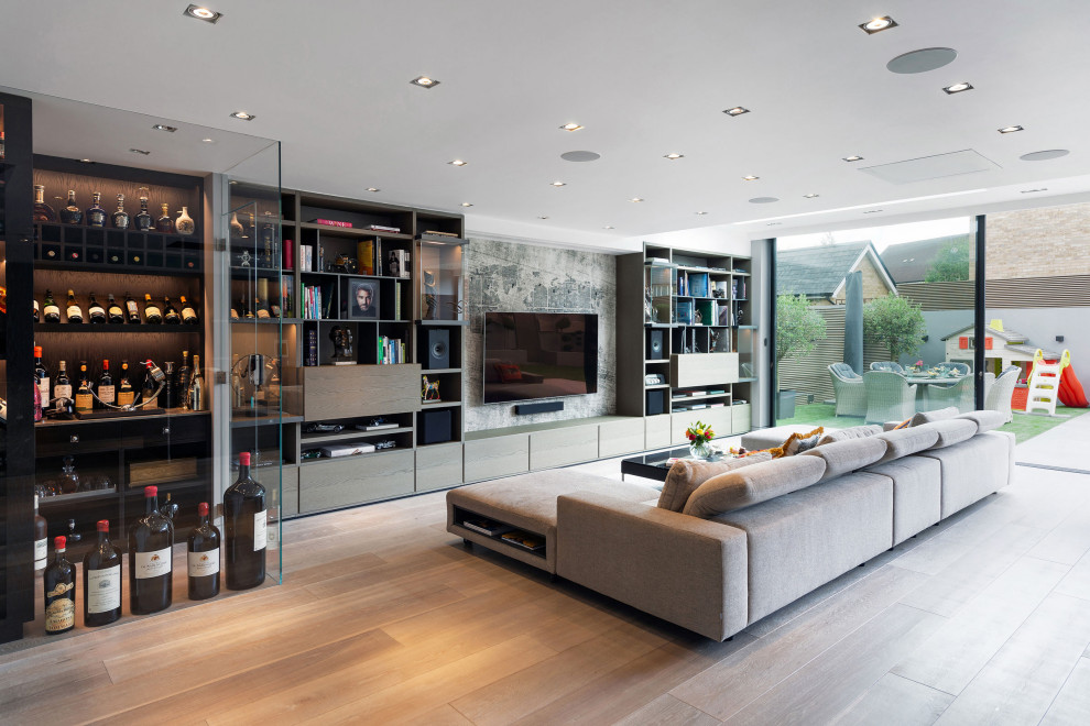 Expansive contemporary open concept family room in London with grey walls, light hardwood floors, no fireplace, a wall-mounted tv and beige floor.