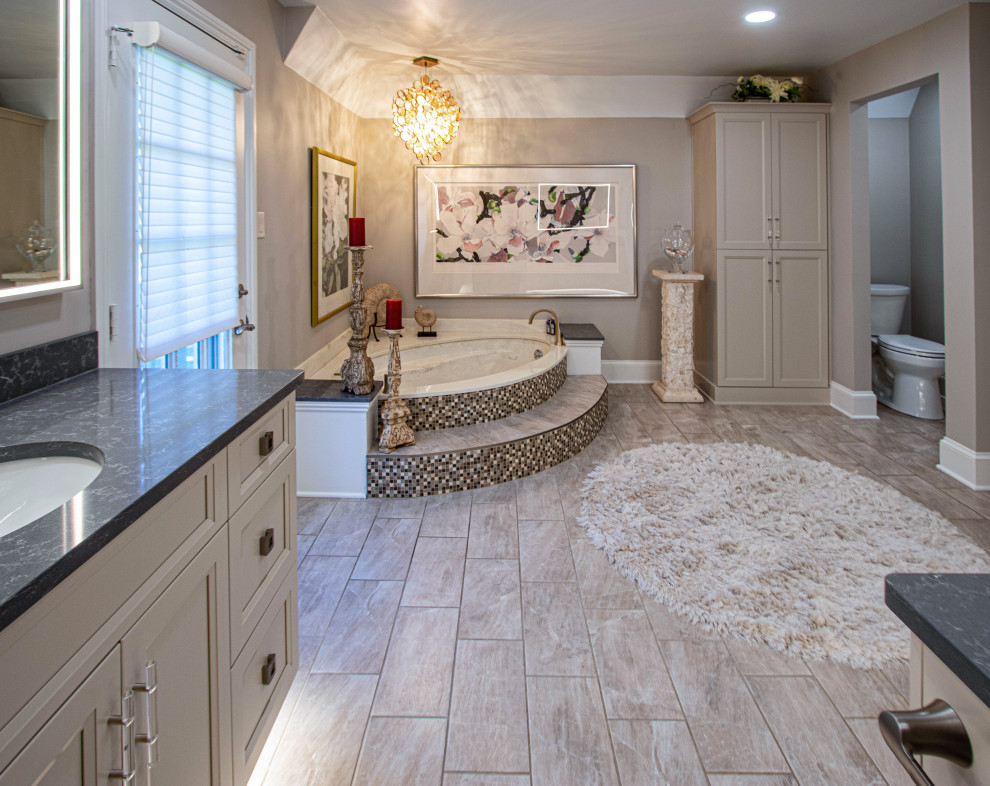 Idée de décoration pour une grande salle de bain principale tradition avec des portes de placard blanches, un bain bouillonnant, une douche d'angle, un carrelage beige, un mur gris, un sol en carrelage de céramique, un lavabo encastré, un plan de toilette en quartz modifié, un sol gris, une cabine de douche à porte battante, un plan de toilette gris, une niche, meuble simple vasque et meuble-lavabo encastré.