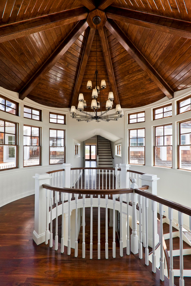 Photo of a large beach style hallway in Other with white walls, dark hardwood floors and brown floor.