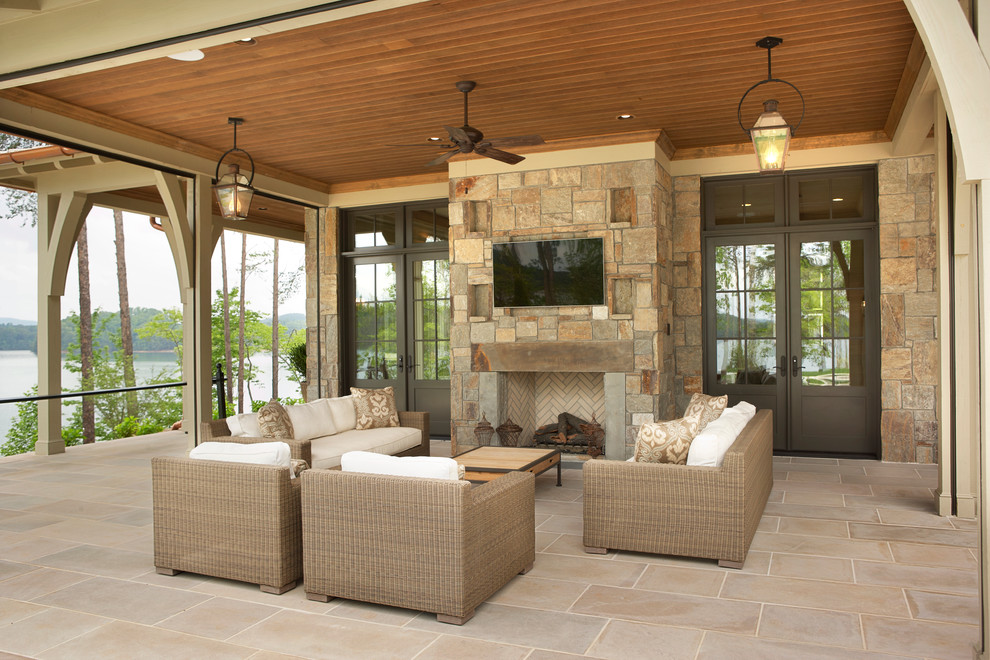 This is an example of a large traditional backyard patio in Other with natural stone pavers and a roof extension.