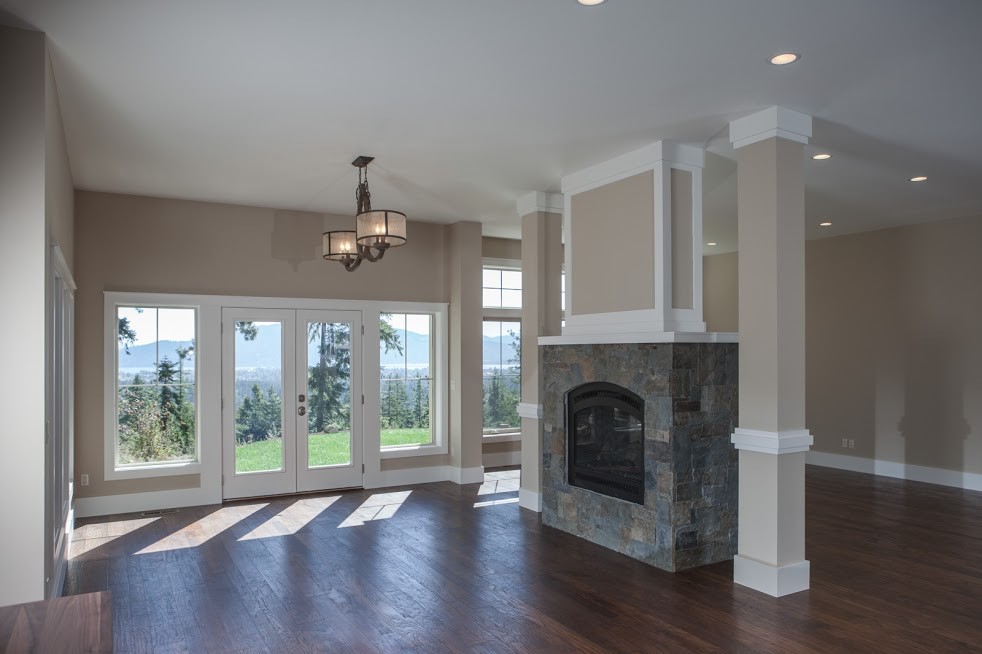 This is an example of a large transitional open concept family room in Grand Rapids with beige walls, dark hardwood floors, a two-sided fireplace and a stone fireplace surround.