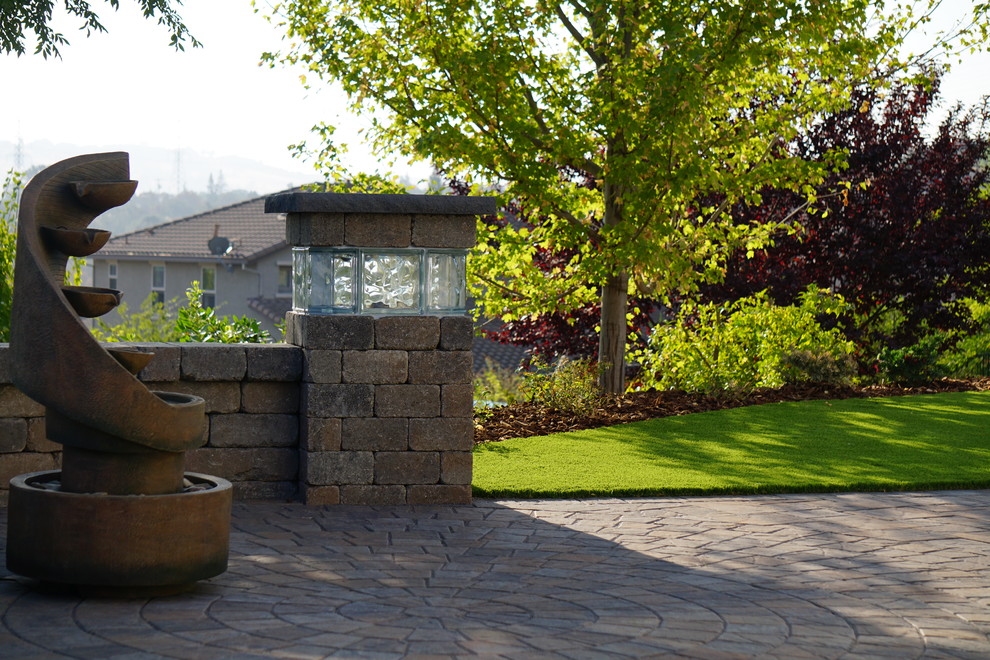Inspiration for a mid-sized transitional backyard patio in Sacramento with a water feature, concrete pavers and no cover.