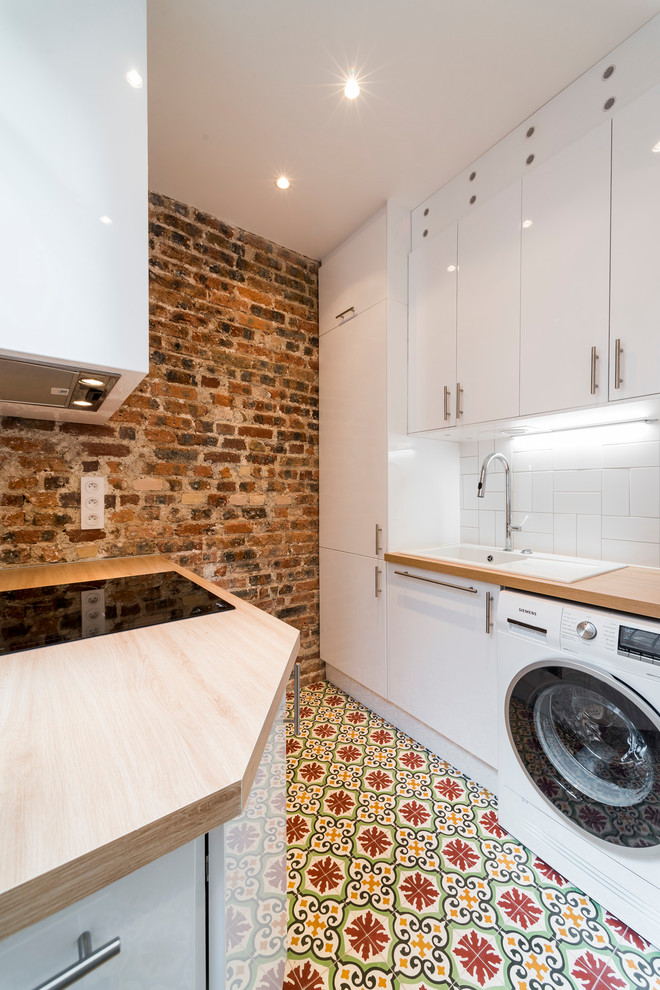 Mediterranean utility room in Paris with a drop-in sink, flat-panel cabinets, white cabinets, wood benchtops, red walls and multi-coloured floor.