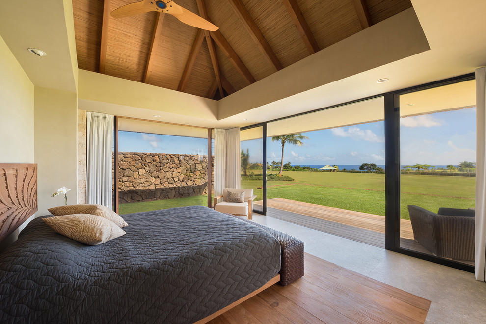 This is an example of a tropical master bedroom in Hawaii with limestone floors, grey floor and beige walls.