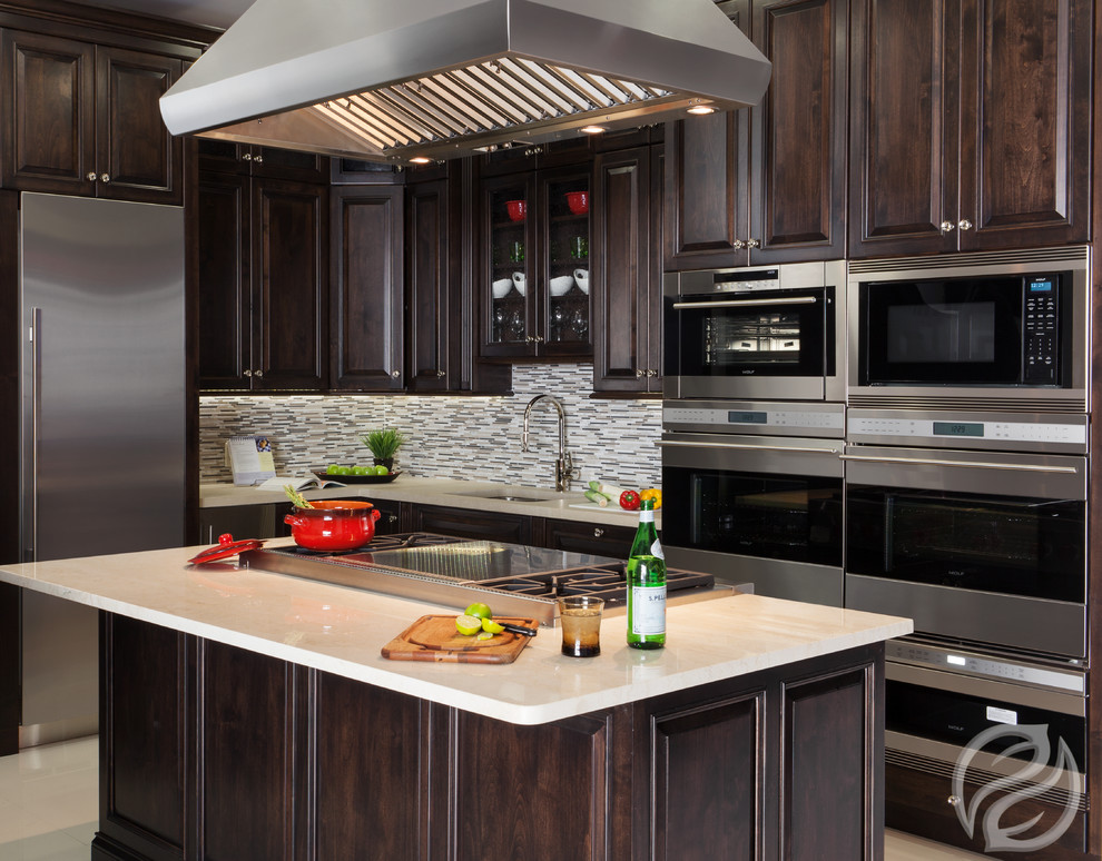 Inspiration for a mid-sized transitional l-shaped porcelain tile open concept kitchen remodel in Chicago with an undermount sink, raised-panel cabinets, dark wood cabinets, quartz countertops, multicolored backsplash, glass tile backsplash, stainless steel appliances and an island