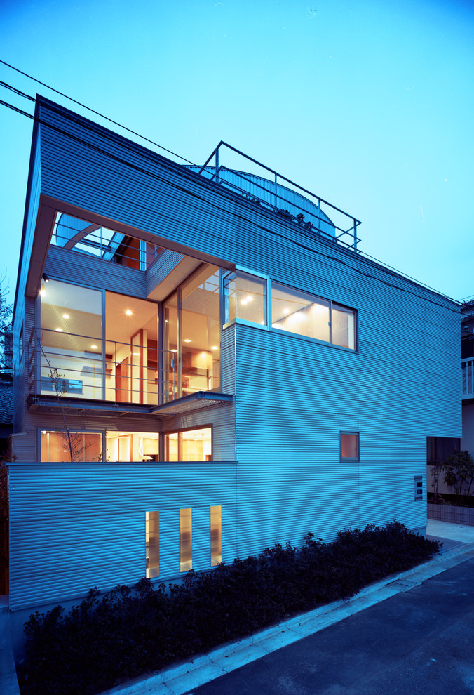 Mid-sized modern three-storey grey duplex exterior in Tokyo with concrete fiberboard siding and a flat roof.