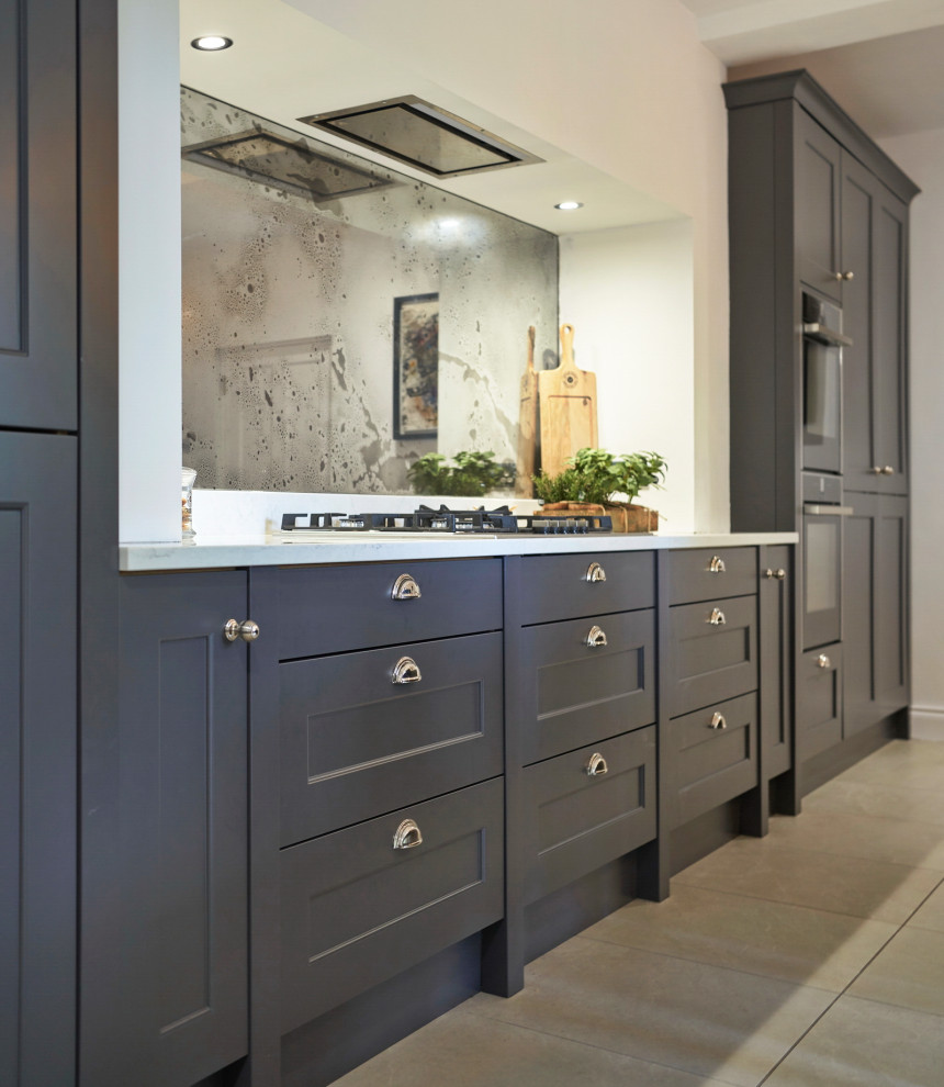 Inspiration for a mid-sized traditional galley eat-in kitchen in Belfast with a farmhouse sink, shaker cabinets, grey cabinets, quartzite benchtops, metallic splashback, glass sheet splashback, black appliances, ceramic floors, with island, beige floor and yellow benchtop.