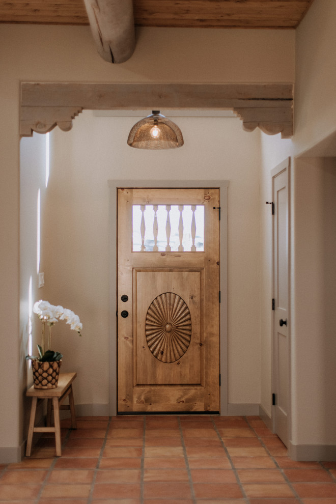 Immagine di una porta d'ingresso stile americano di medie dimensioni con pareti beige, pavimento in terracotta, una porta singola, una porta in legno chiaro, pavimento arancione e travi a vista