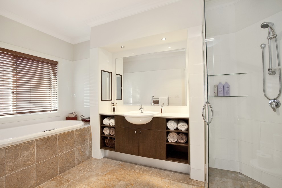 Mid-sized contemporary master bathroom in Sunshine Coast with a drop-in tub, a corner shower, white tile, brown floor, furniture-like cabinets, brown cabinets, ceramic tile, white walls, ceramic floors, a drop-in sink, marble benchtops, a hinged shower door and white benchtops.