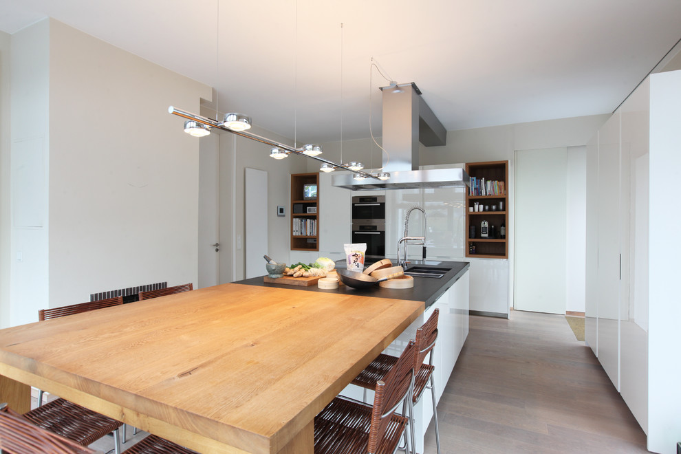 Inspiration for a mid-sized contemporary l-shaped open plan kitchen in Frankfurt with an undermount sink, flat-panel cabinets, white cabinets, white splashback, painted wood floors and with island.
