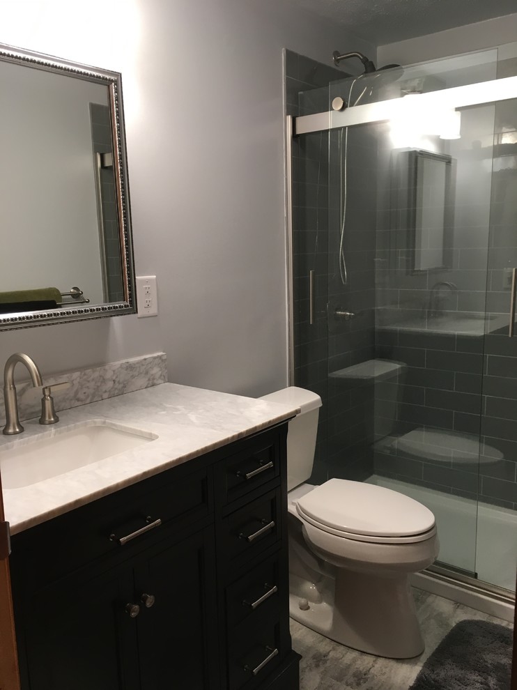 This is an example of a small modern master bathroom in Other with raised-panel cabinets, grey cabinets, a curbless shower, a one-piece toilet, gray tile, grey walls, vinyl floors, an undermount sink, marble benchtops, grey floor, a sliding shower screen and white benchtops.