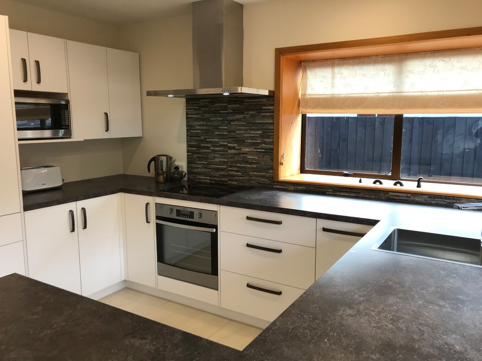 Mid-sized contemporary U-shaped separate kitchen in Christchurch With a Single-bowl Sink, Flat-panel Cabinets, White Cabinets, Laminate Benchtops, Multi-Coloured Splashback, Stone Tile Splashback, Stainless Steel Appliances, Porcelain Floors, no Island, White Floor and Multi-Coloured Benchtop.