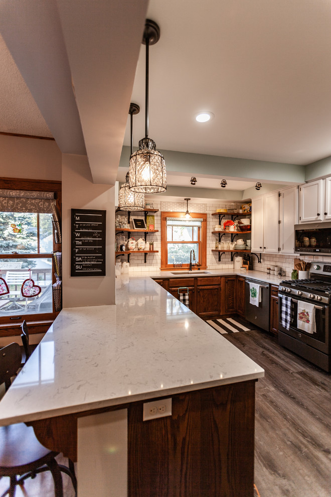 Photo of a mid-sized traditional u-shaped eat-in kitchen in Minneapolis with an undermount sink, shaker cabinets, medium wood cabinets, quartz benchtops, white splashback, subway tile splashback, stainless steel appliances, vinyl floors, a peninsula, grey floor and white benchtop.