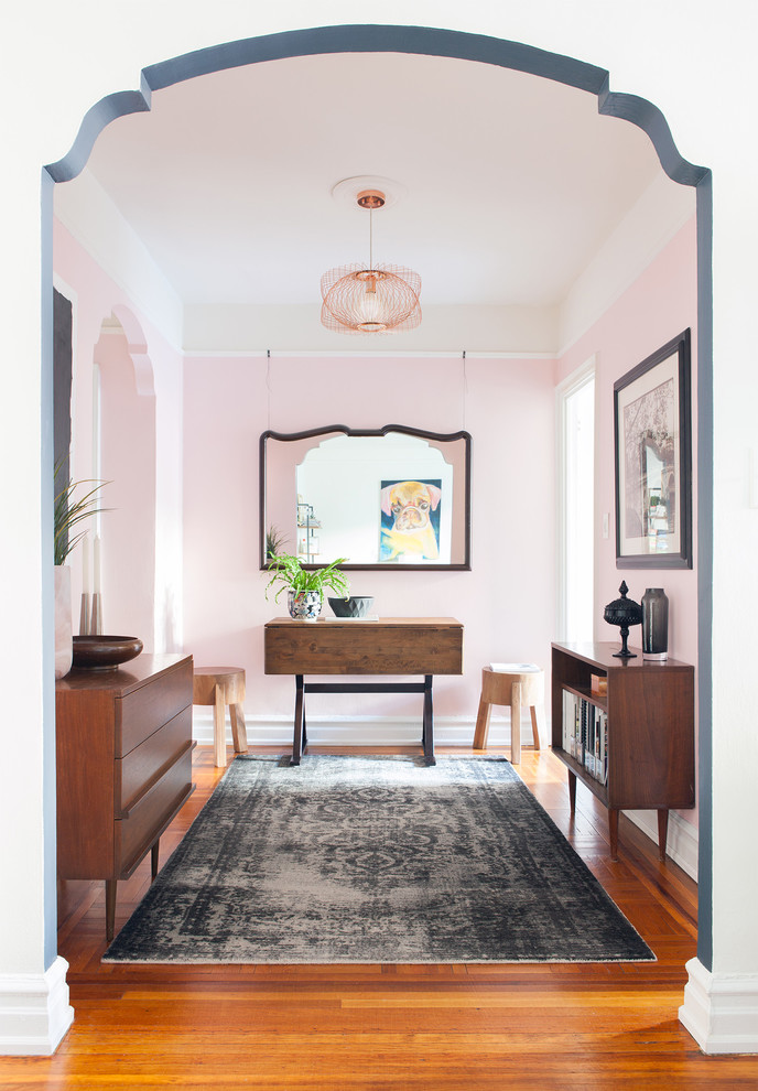 Photo of an eclectic foyer in New York with pink walls, medium hardwood floors and brown floor.