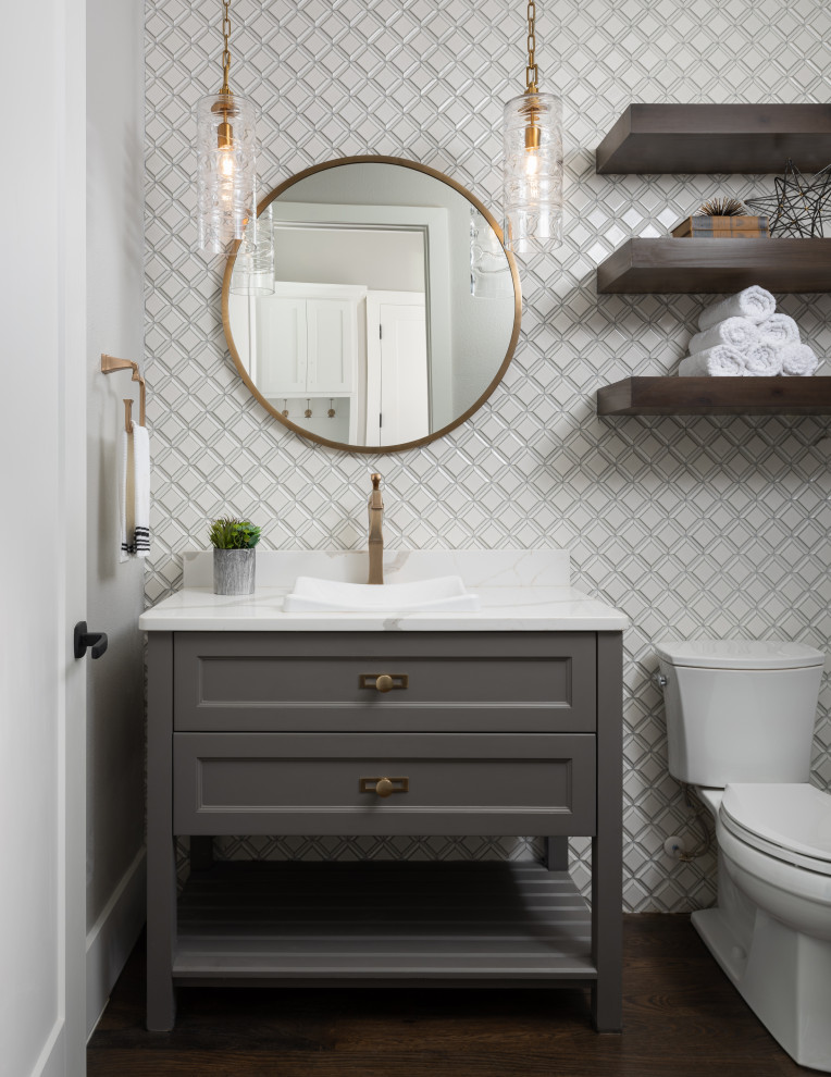 This is an example of a transitional powder room in Dallas with recessed-panel cabinets, grey cabinets, white tile, dark hardwood floors, a vessel sink, brown floor, white benchtops and a freestanding vanity.