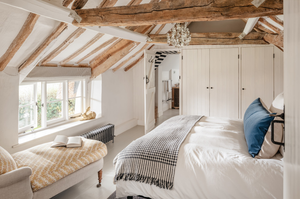 Ejemplo de dormitorio principal de estilo de casa de campo grande con paredes blancas, suelo de madera clara, vigas vistas y madera