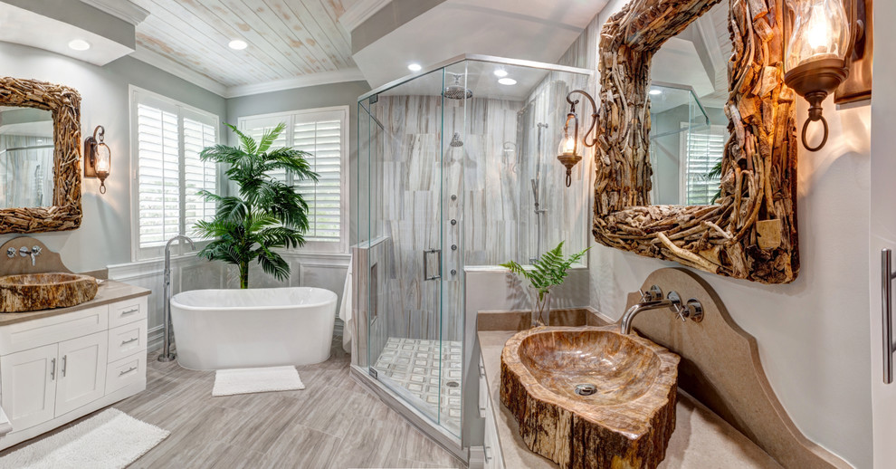 Photo of a mid-sized tropical master bathroom in Miami with shaker cabinets, white cabinets, a freestanding tub, a corner shower, a two-piece toilet, beige tile, porcelain tile, grey walls, ceramic floors, a vessel sink and engineered quartz benchtops.