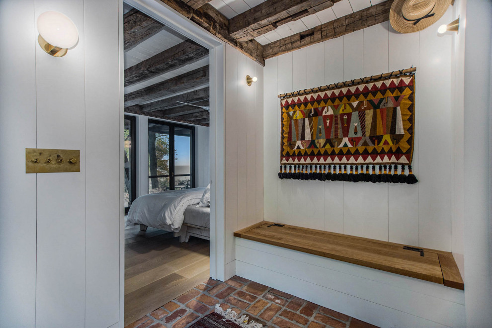 Mountain style brick floor, red floor, exposed beam and shiplap wall foyer photo in Grand Rapids with white walls