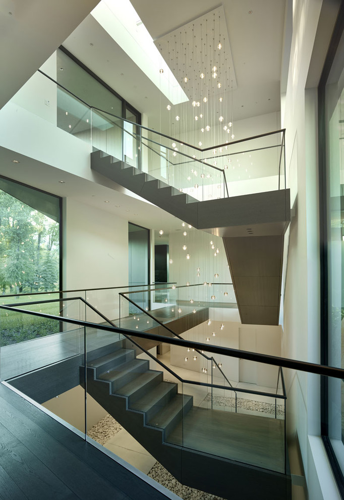This is an example of an expansive contemporary wood floating staircase in Other with wood risers and glass railing.