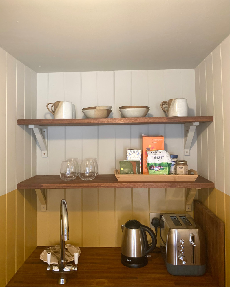Photo of a small beach style single-wall kitchen pantry in Kent with open cabinets, dark wood cabinets, wood benchtops, yellow splashback, shiplap splashback, stainless steel appliances, vinyl floors, no island, beige floor and brown benchtop.
