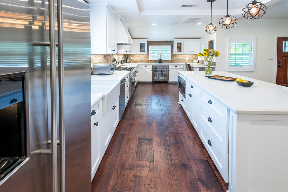 Inspiration for a mid-sized contemporary l-shaped eat-in kitchen in Los Angeles with a farmhouse sink, shaker cabinets, white cabinets, quartz benchtops, red splashback, brick splashback, stainless steel appliances, dark hardwood floors and with island.