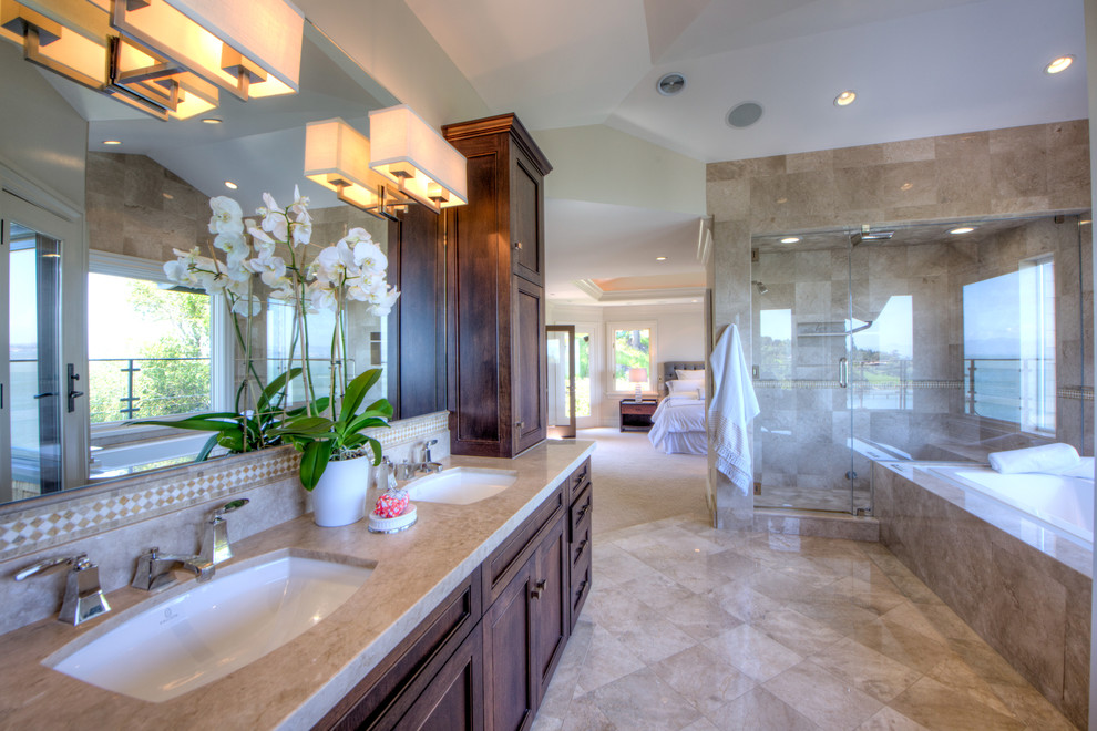 This is an example of a large traditional bathroom in San Francisco with shaker cabinets, brown cabinets, a drop-in tub, a double shower, a one-piece toilet, beige tile, travertine, beige walls, travertine floors, an undermount sink, beige floor, an open shower, a shower seat, a double vanity, a built-in vanity, wood and wood walls.