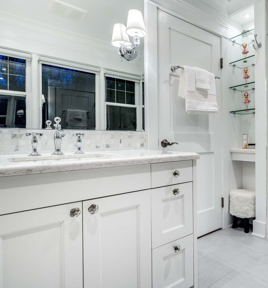 Example of a mid-sized transitional l-shaped medium tone wood floor eat-in kitchen design in Vancouver with a farmhouse sink, shaker cabinets, white cabinets, quartzite countertops, white backsplash, stone tile backsplash, stainless steel appliances and a peninsula