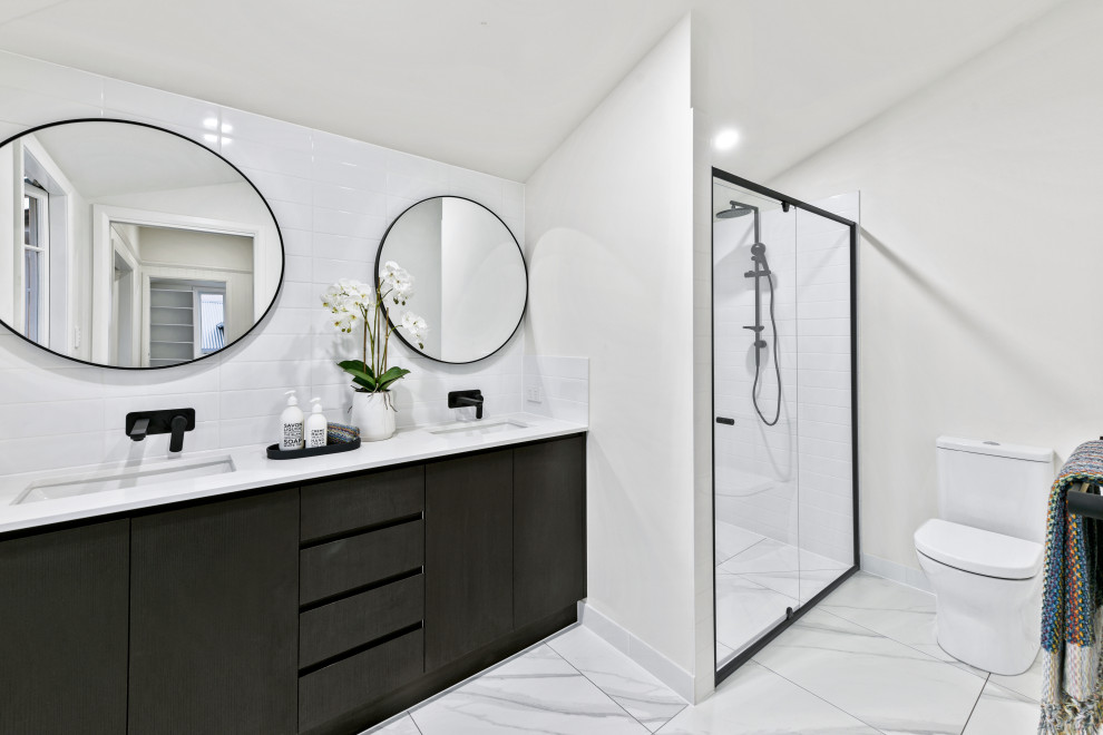 Design ideas for a mid-sized traditional master bathroom in Brisbane with furniture-like cabinets, dark wood cabinets, a freestanding tub, an alcove shower, a one-piece toilet, white tile, subway tile, white walls, porcelain floors, an undermount sink, engineered quartz benchtops, white floor, a hinged shower door and white benchtops.