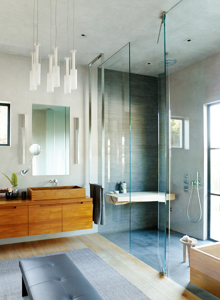 Design ideas for a contemporary master bathroom in San Francisco with flat-panel cabinets, dark wood cabinets, a freestanding tub, a curbless shower, gray tile, grey walls, light hardwood floors, a vessel sink, beige floor and a hinged shower door.