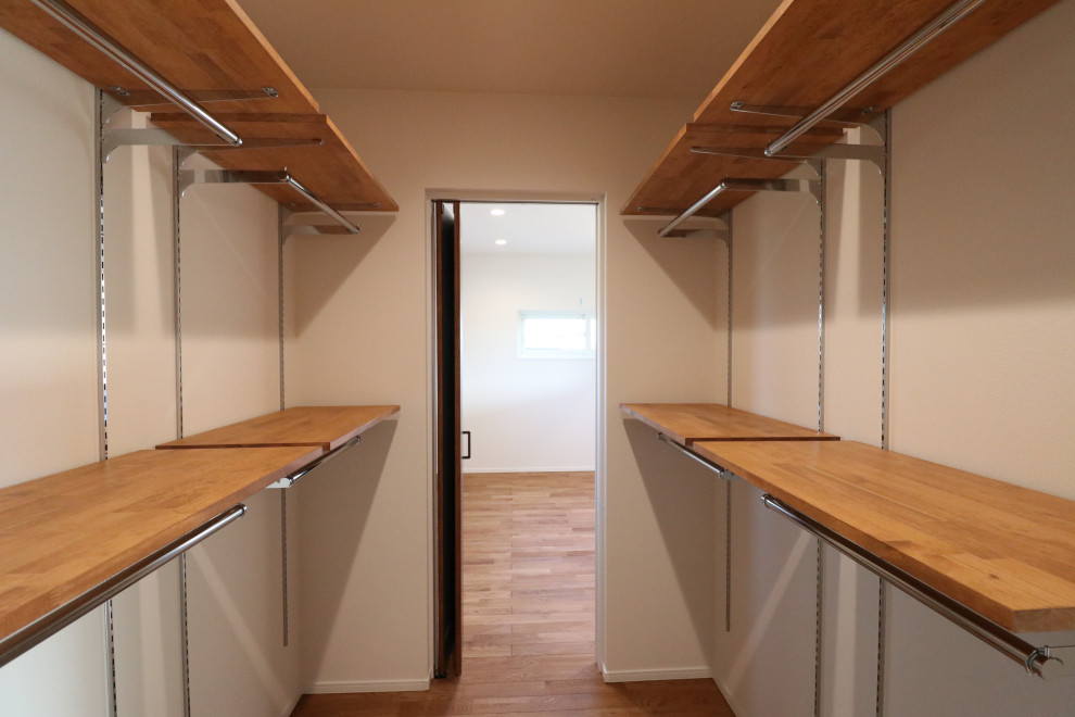 Idee per una cabina armadio unisex industriale con nessun'anta, ante in legno scuro, pavimento in legno massello medio e soffitto in carta da parati