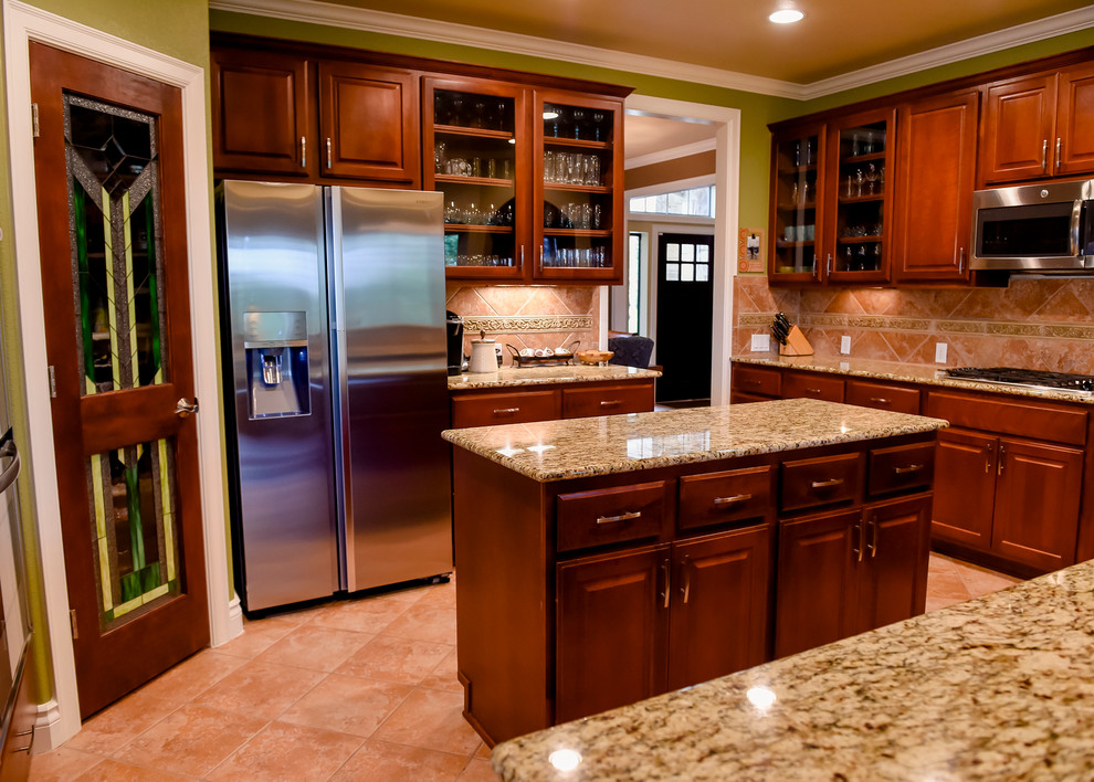 Mid-sized arts and crafts l-shaped eat-in kitchen in Miami with raised-panel cabinets, dark wood cabinets, granite benchtops, multi-coloured splashback, ceramic splashback, stainless steel appliances, terra-cotta floors, with island and beige floor.