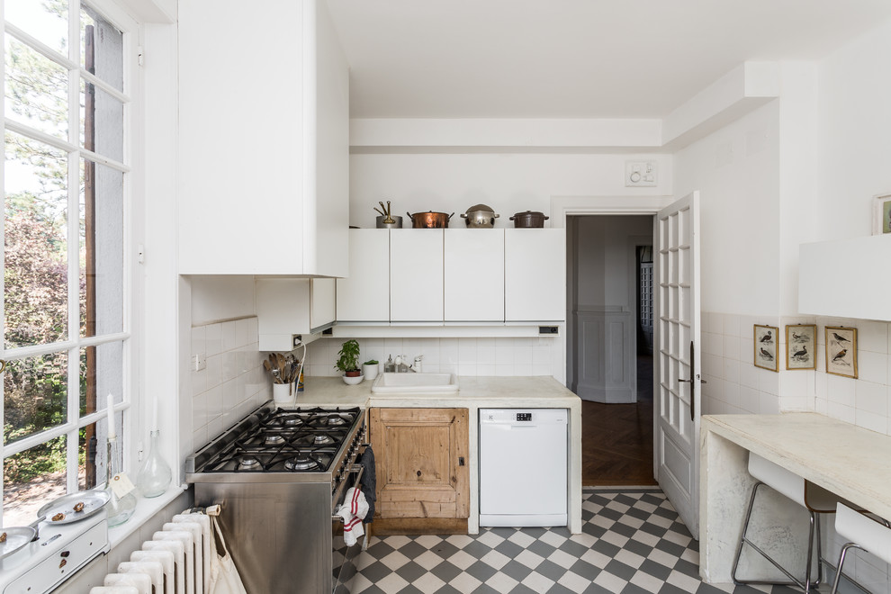 Design ideas for a mid-sized transitional l-shaped separate kitchen in Other with white cabinets, concrete benchtops, white splashback, ceramic splashback, a drop-in sink, flat-panel cabinets, stainless steel appliances and no island.