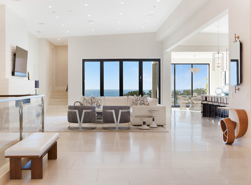 Photo of a large contemporary open concept family room in Orange County with white walls, ceramic floors, a standard fireplace, a tile fireplace surround, a wall-mounted tv and beige floor.
