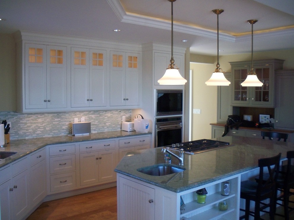 Photo of a large transitional eat-in kitchen in Boston with an undermount sink, shaker cabinets, white cabinets, granite benchtops, blue splashback, glass tile splashback, stainless steel appliances, medium hardwood floors and with island.