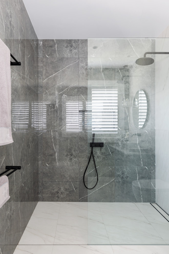 Foto på ett mellanstort maritimt vit badrum med dusch, med luckor med infälld panel, svarta skåp, en kantlös dusch, en vägghängd toalettstol, vit kakel, keramikplattor, vita väggar, ett nedsänkt handfat, granitbänkskiva och dusch med gångjärnsdörr