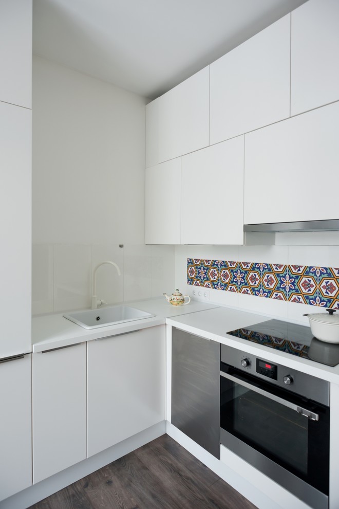 This is an example of a small contemporary l-shaped separate kitchen in Moscow with white cabinets, a drop-in sink, flat-panel cabinets, multi-coloured splashback, stainless steel appliances and no island.
