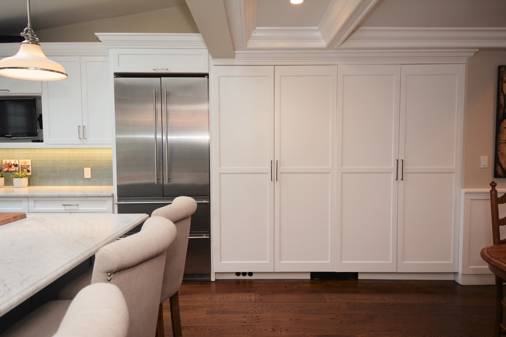 Inspiration for a large transitional l-shaped medium tone wood floor eat-in kitchen remodel in New York with recessed-panel cabinets, white cabinets, marble countertops, blue backsplash, glass tile backsplash, stainless steel appliances, an island and an undermount sink