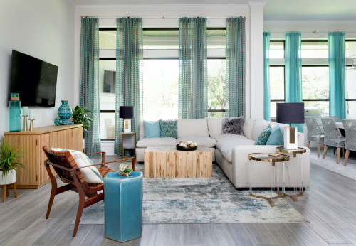 A cozy living room with blue curtains, white furniture, bright colour.
