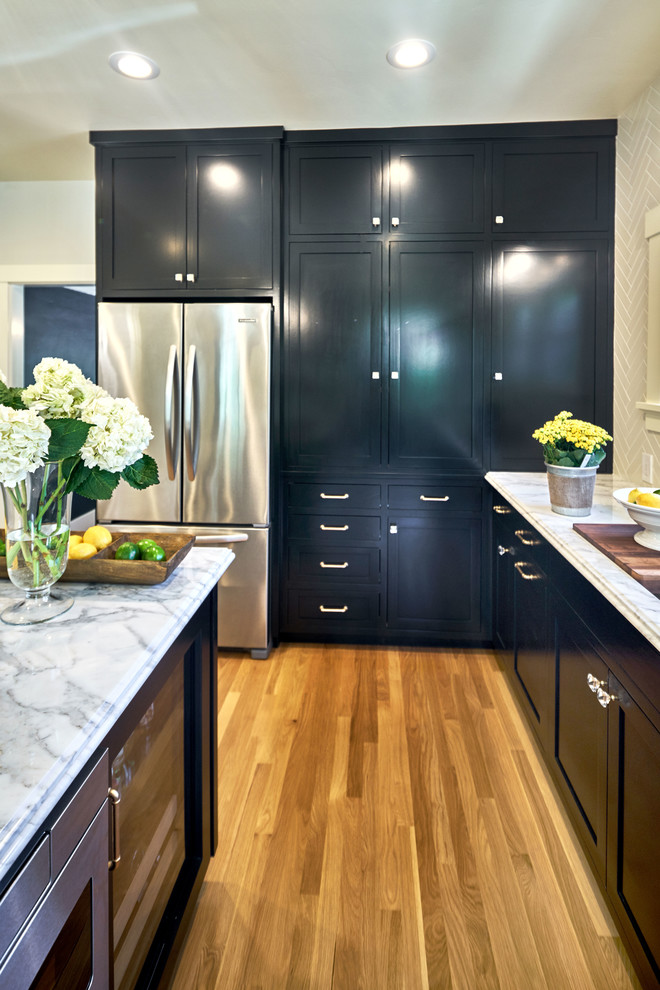 Inspiration for a mid-sized transitional single-wall separate kitchen in San Francisco with an undermount sink, shaker cabinets, black cabinets, marble benchtops, subway tile splashback, stainless steel appliances, light hardwood floors and with island.