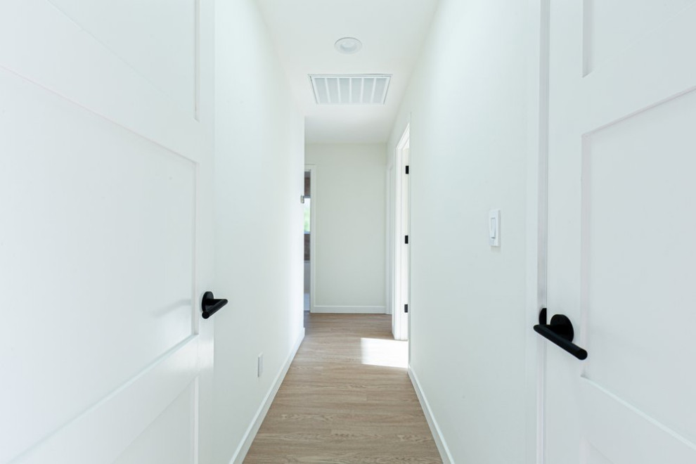 Exemple d'un couloir moderne avec un mur blanc, parquet clair et un sol marron.