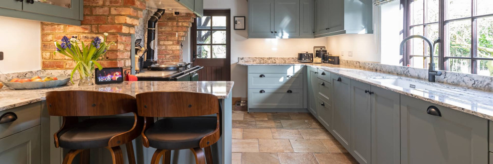 Design ideas for a large country u-shaped separate kitchen in Buckinghamshire with shaker cabinets, black cabinets, quartzite benchtops, black appliances and terra-cotta floors.