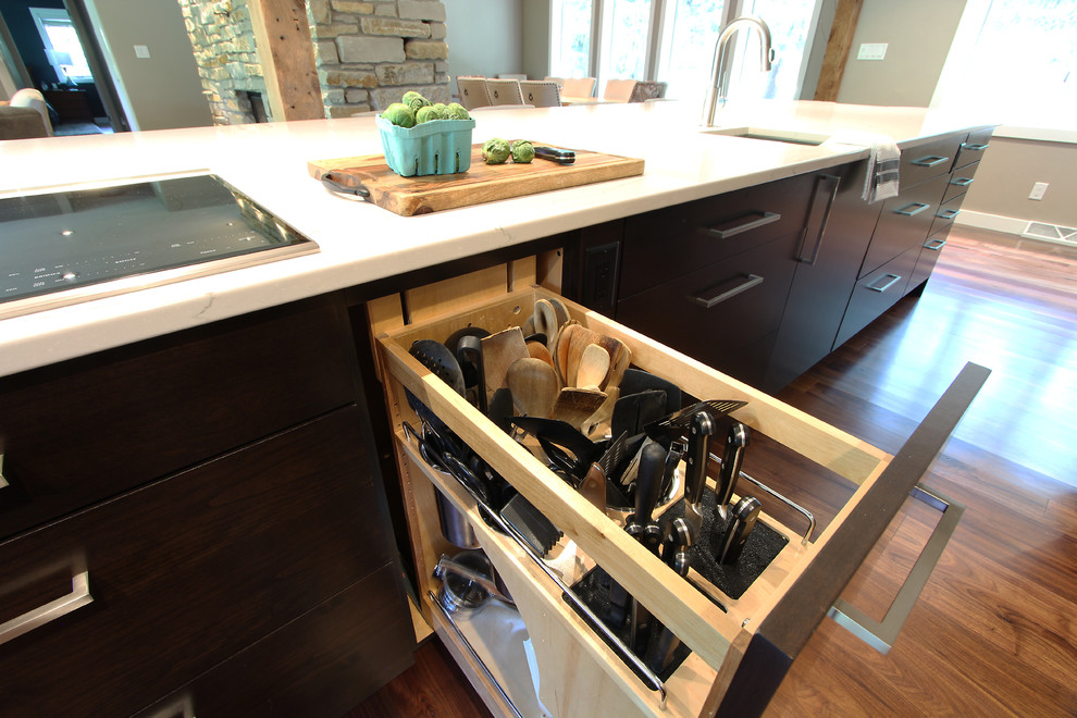 Large transitional l-shaped medium tone wood floor and brown floor open concept kitchen photo with an undermount sink, flat-panel cabinets, medium tone wood cabinets, quartz countertops, gray backsplash, porcelain backsplash, stainless steel appliances and an island